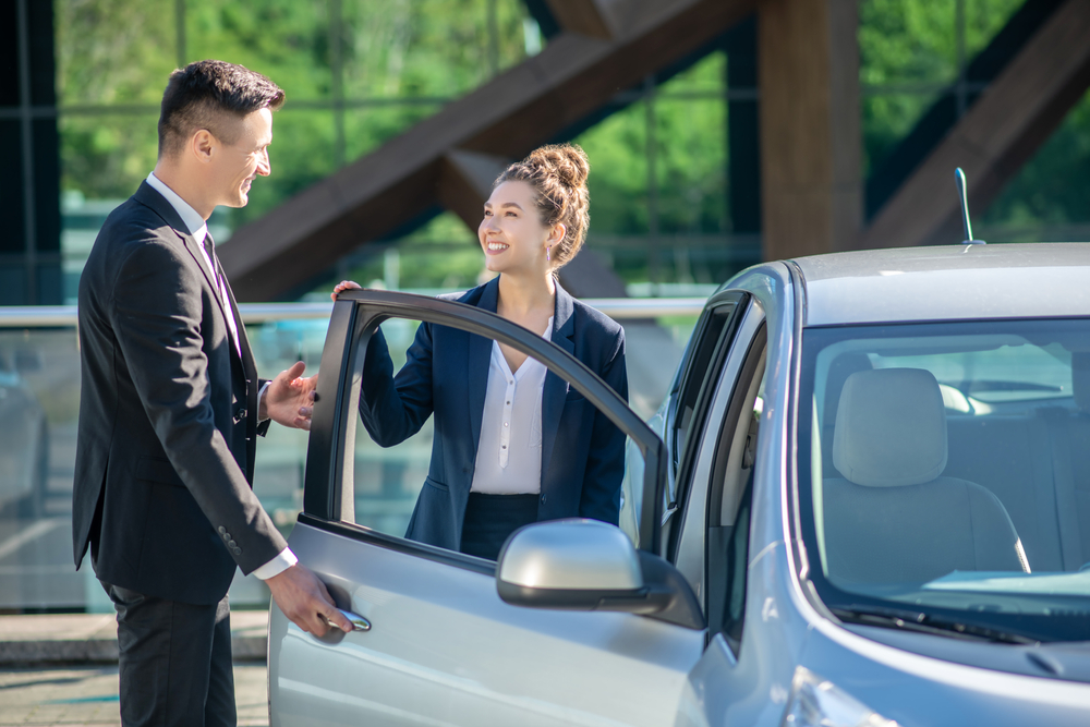 Man opening the car door for a smiling woman.